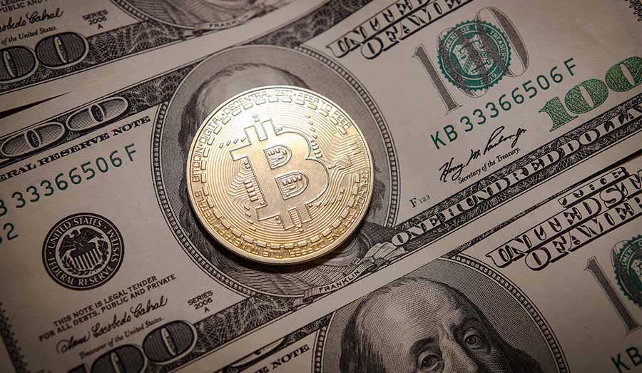 Nota de dólar com um bitcoin em cima.
