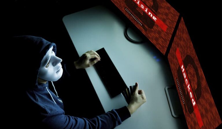 Hacker de máscara olhando a tela do computador escrito phishing.