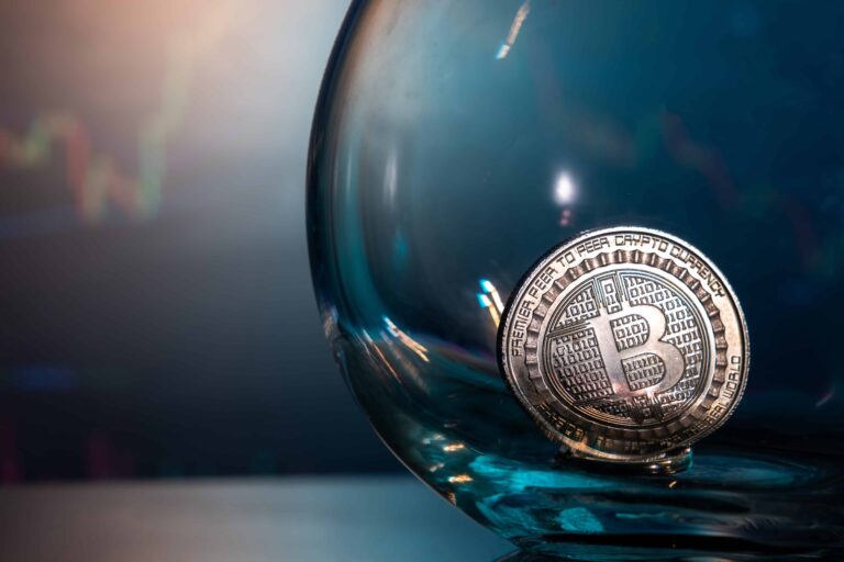 closeup of a silver bitcoin on a blue reflective surface in a glass and the histogram of currency scaled