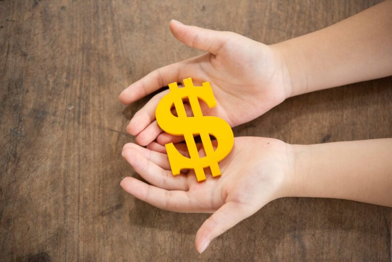 child holding yellow dollar sign scaled