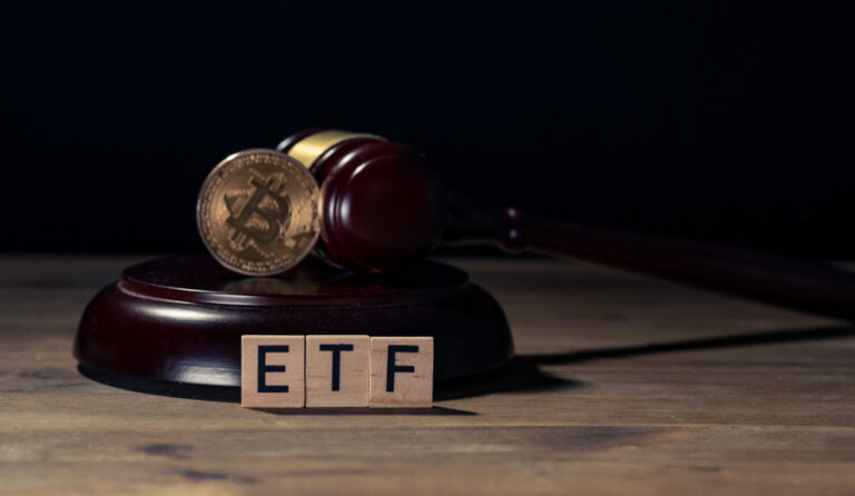 Blocos de madeira formando a palavra etf ao lado de um Bitcoin.